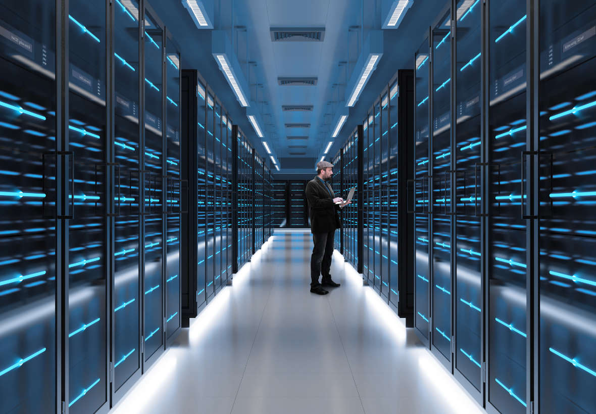Person stands in front of a server with a laptop Person stands in front of a server with a laptop