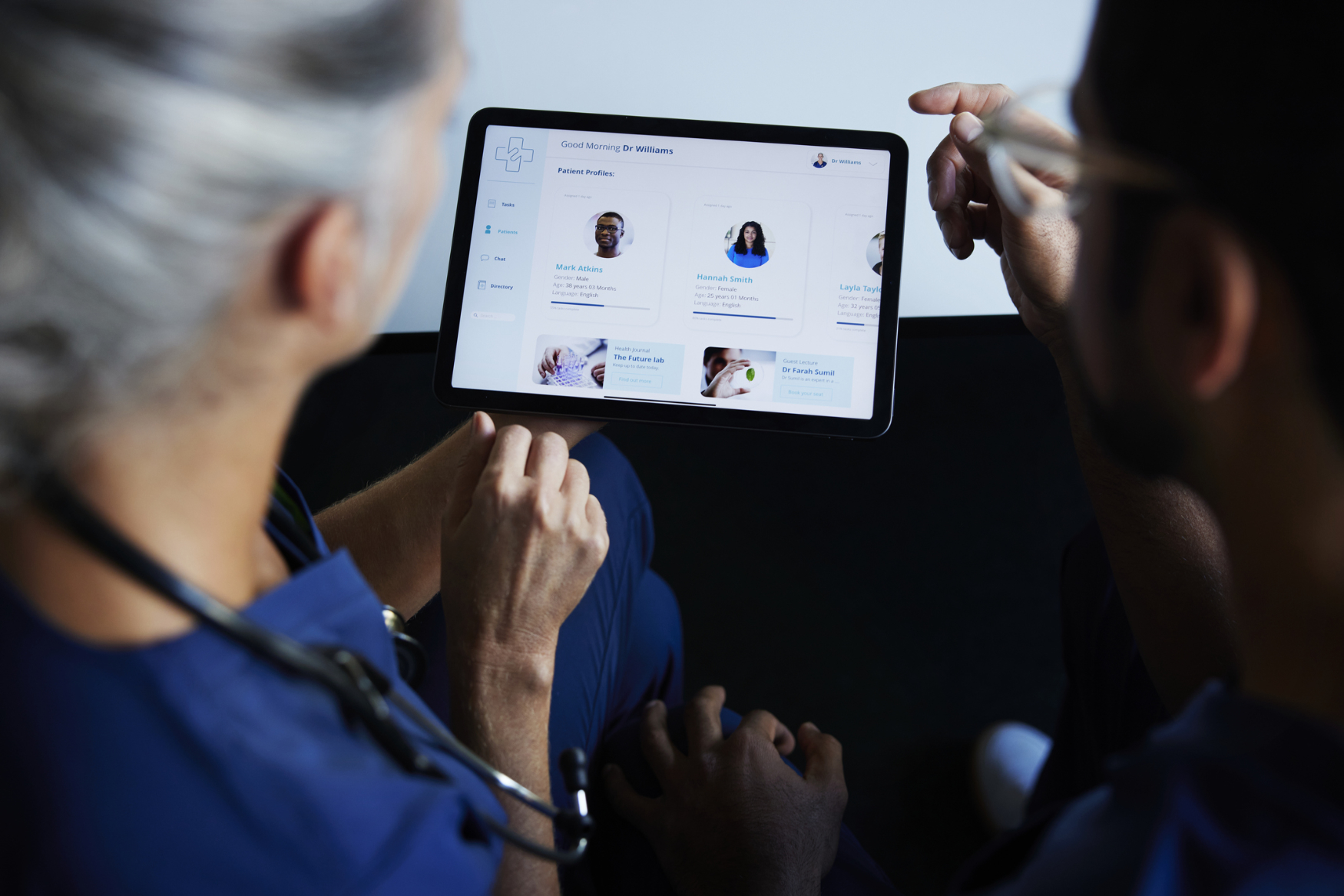 Doctors are sitting at the table looking at a tablet