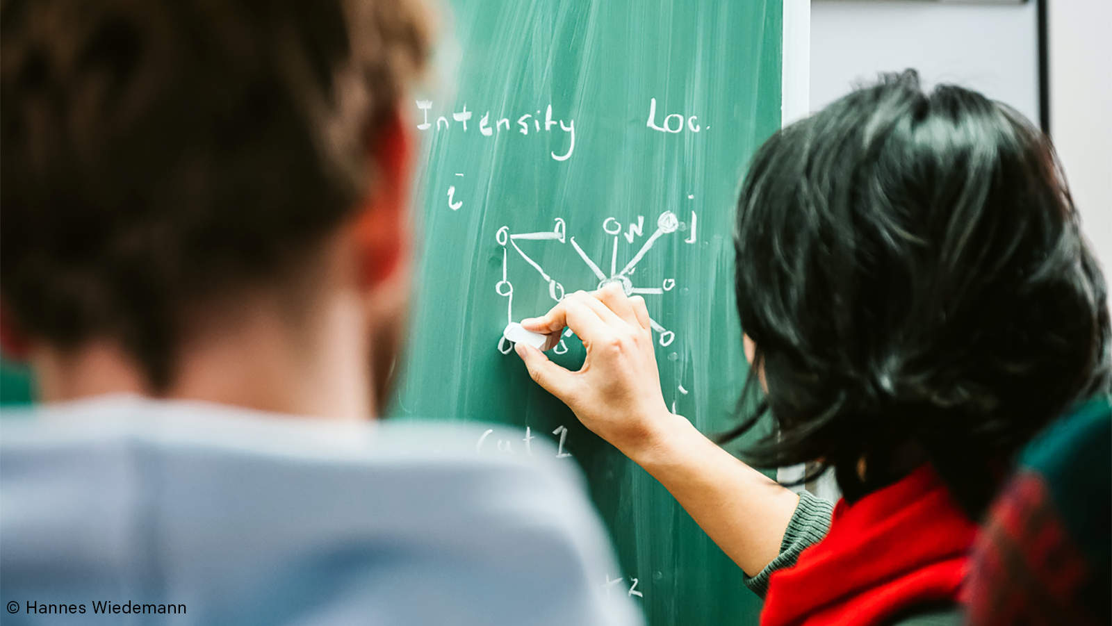 Interdisziplinärer Austausch Foto von zwei Wissenschaftlern des Max-Planck-Instituts, die an einer Tafel Formeln aufschreiben