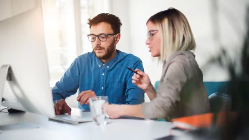 A man and a woman working together at a computer.