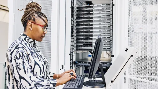 A woman sits at the computer and works on the server.