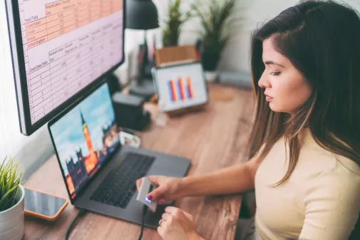 Eine Frau arbeitet am Computer und benutzt einen Fingerabdruckleser.