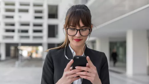 Frau tippt auf Smartphone mit Kopfhörer i den Ohrern draussen Frau tippt auf Smartphone mit Kopfhörer i den Ohrern draussen