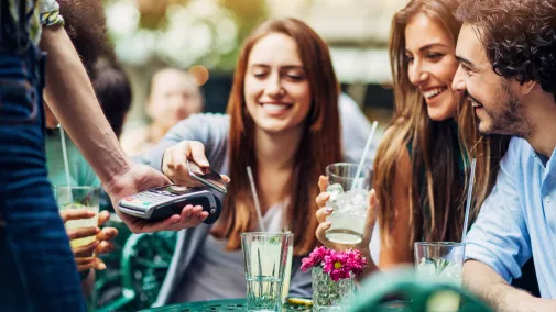 women an men paying with smartphone in a bar outside women an men paying with smartphone in a bar outside