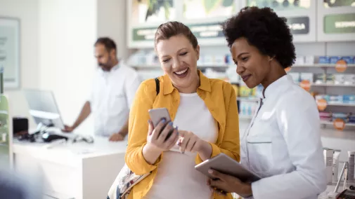Zwei Frauen stehen mit Smartphone in Apotheke Zwei Frauen stehen mit Smartphone in Apotheke