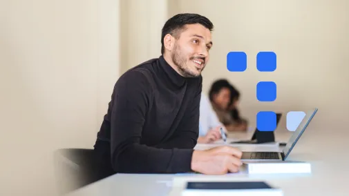 Mann sitzt am Schreibtisch vor dem Laptop und schreibt sich etwas auf. 