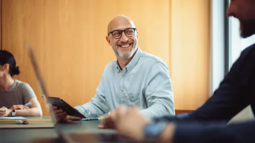 A man holds an iPad in his hand and smiles