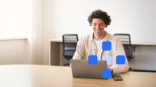 Ein Mann arbeitet am Laptop und lächelt