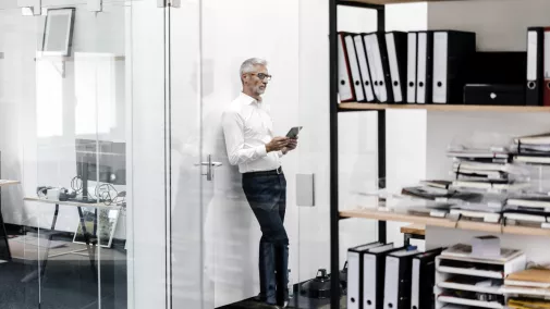 Mann steht mit Tabet im Büro