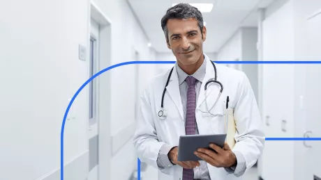 Man in smock holding a tablet.