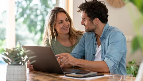 women and man sitting with a tablet on a table at home