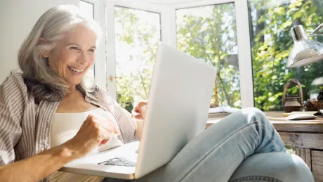 Frau Senior sitzt mit Notebook draussen