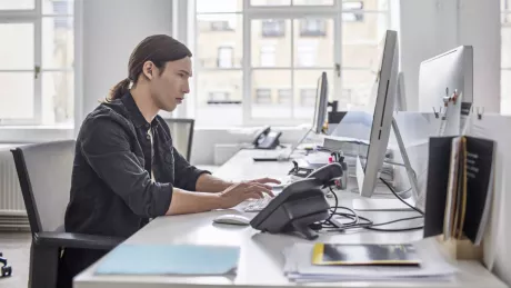 Mann sitzt am Computer am Schreibtisch im Büro