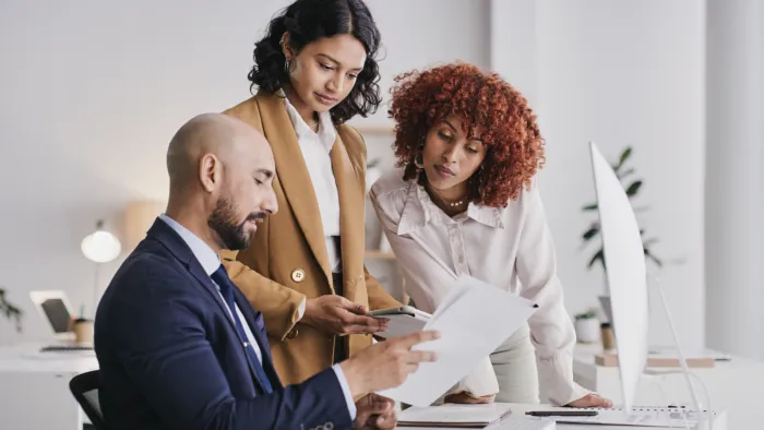 Drei Personen mit Tablet und Dokumenten