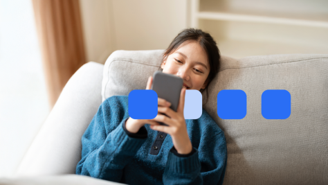 Frau liegt auf dem Sofa und schaut aufs Handy.