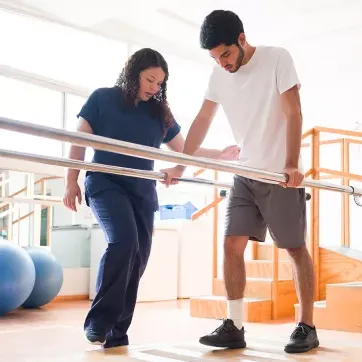 Foto einer Physiotherapeutin, die einen männlichen Patienten in einer Physiotherapie-Praxis behandelt