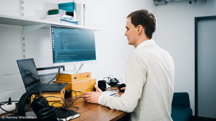 Foto von Dr. Eric Schulz vom Max-Plack-Institut, der vor einem Computer steht und daran arbeitet