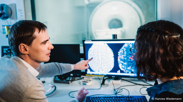 Foto von zwei Wissenschaftlern des Max-Planck-Instituts, die sich an einem Monitor eine Funktionelle Magnetresonanztomografie (fMRT)-Aufnahme ansehen
